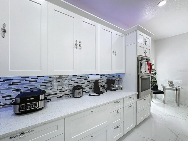 3911 Auburndale Ave, Orlando, FL 32839 - kitchen featuring stainless steel double oven, decorative backsplash, light stone countertops, and white cabinets