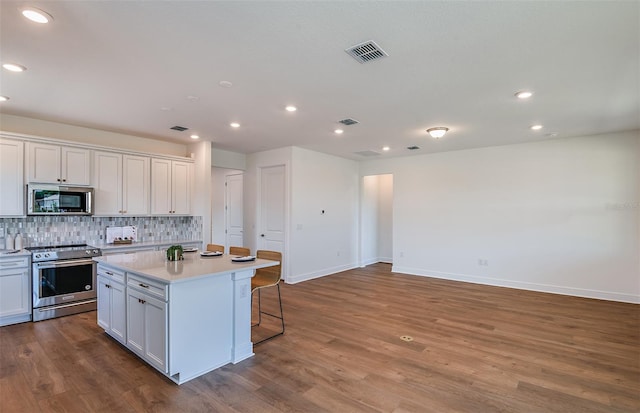 5295 SW 87th Ter, Ocala, FL 34481 - kitchen with stainless steel appliances, tasteful backsplash, a kitchen island, light countertops, and dark wood-style flooring