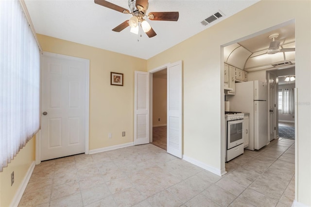 kitchen with white cabinetry, ceiling fan, light tile patterned flooring, and white appliances