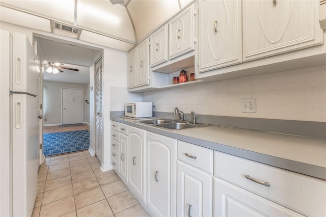 kitchen featuring sink, white appliances, light tile patterned floors, tasteful backsplash, and white cabinets