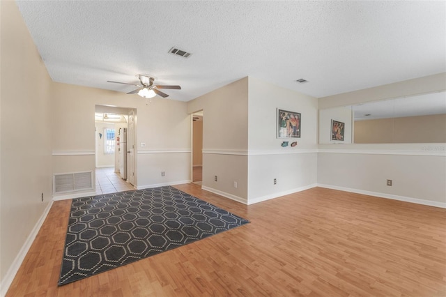 empty room featuring ceiling fan, wood-type flooring, and a textured ceiling