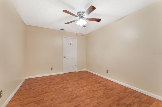 empty room with a textured ceiling, light hardwood / wood-style floors, and ceiling fan