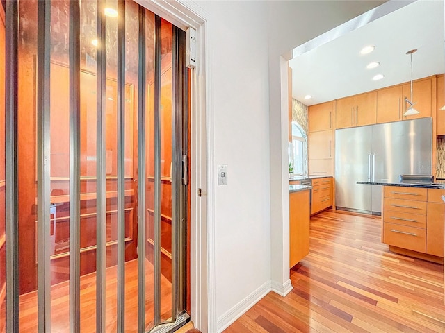 kitchen featuring high end fridge, light hardwood / wood-style flooring, and decorative light fixtures