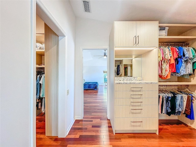 spacious closet with dark hardwood / wood-style floors and ceiling fan