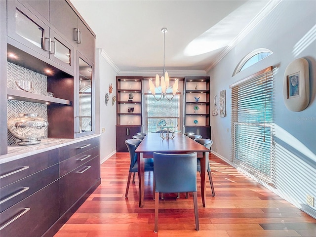 dining room with ornamental molding, a notable chandelier, and light hardwood / wood-style flooring