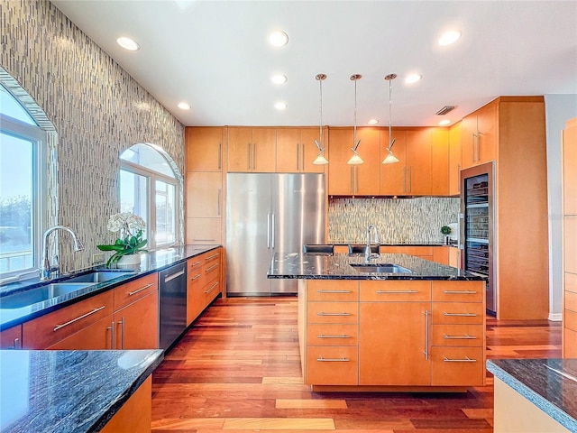 kitchen featuring hanging light fixtures, light hardwood / wood-style flooring, stainless steel appliances, and sink