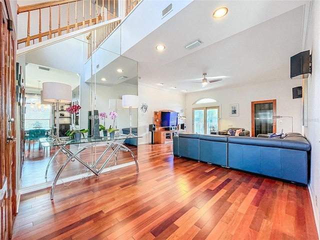 living room with ornamental molding, a towering ceiling, hardwood / wood-style floors, and ceiling fan