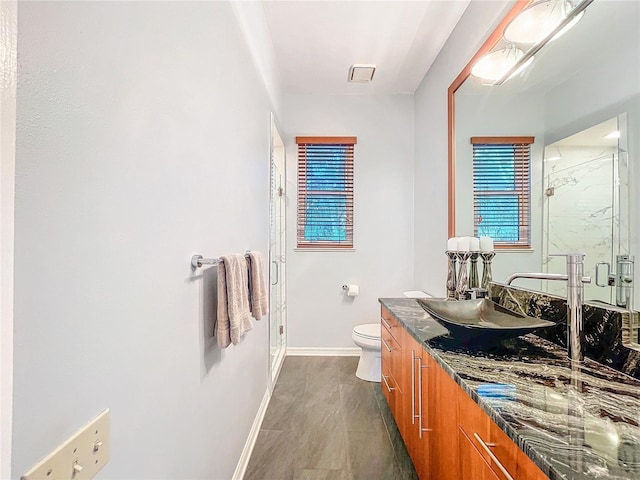 bathroom with hardwood / wood-style flooring, vanity, toilet, and an enclosed shower