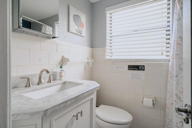 bathroom with vanity, a wealth of natural light, and tile walls