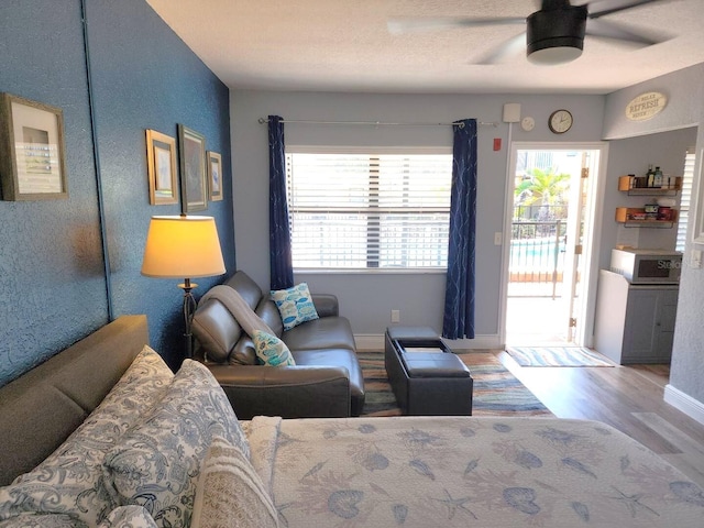 living room featuring wood finished floors, baseboards, and ceiling fan