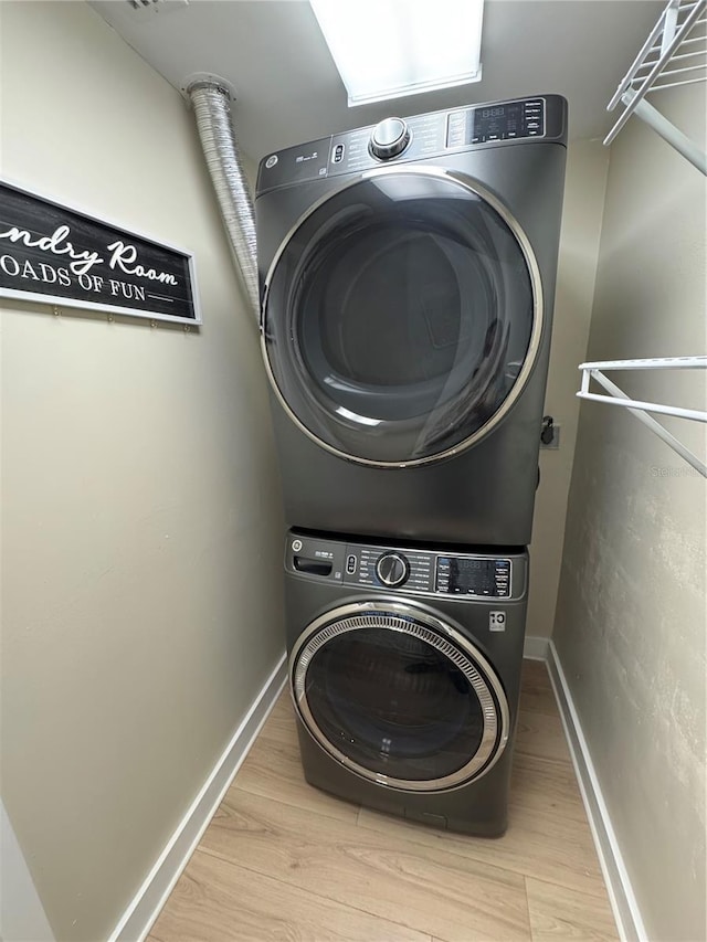 clothes washing area featuring stacked washing maching and dryer and light hardwood / wood-style floors