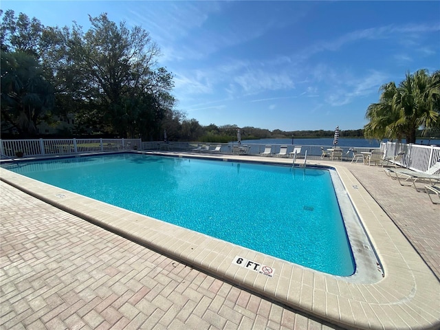 view of swimming pool with a water view and a patio area