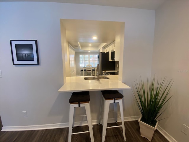 kitchen featuring white cabinetry, dark hardwood / wood-style flooring, a kitchen breakfast bar, and kitchen peninsula