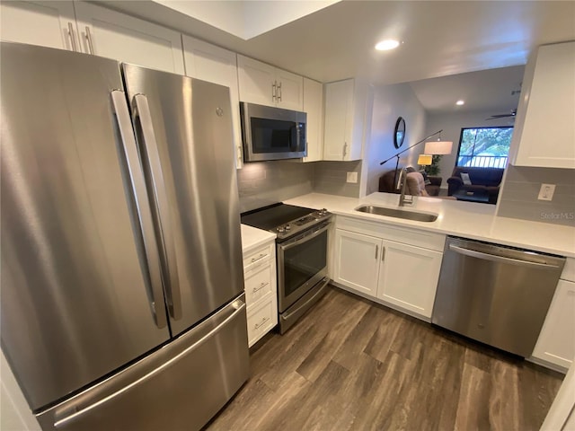 kitchen with appliances with stainless steel finishes, dark hardwood / wood-style floors, white cabinetry, sink, and backsplash