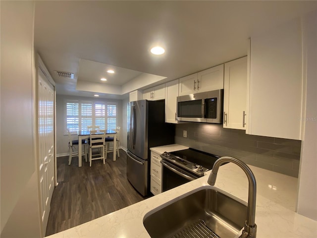 kitchen featuring sink, white cabinetry, tasteful backsplash, a raised ceiling, and stainless steel appliances