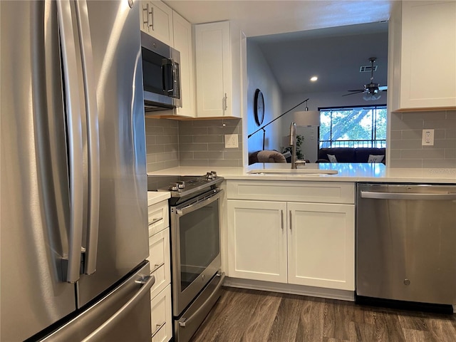 kitchen with sink, dark wood-type flooring, ceiling fan, appliances with stainless steel finishes, and white cabinetry