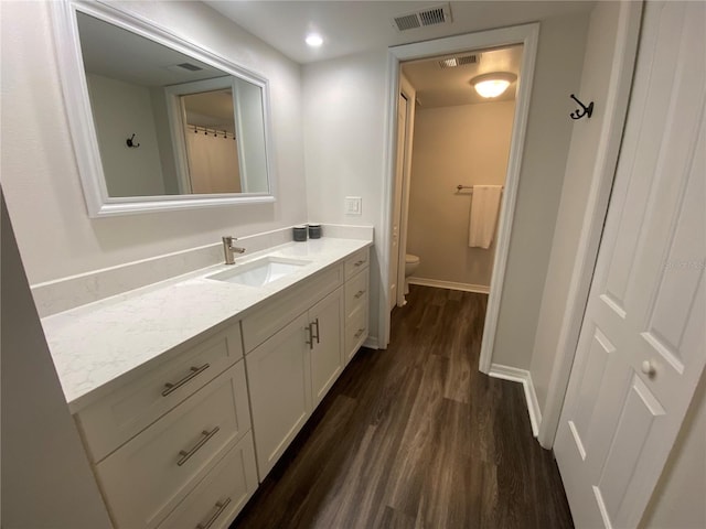 bathroom featuring wood-type flooring, toilet, and vanity