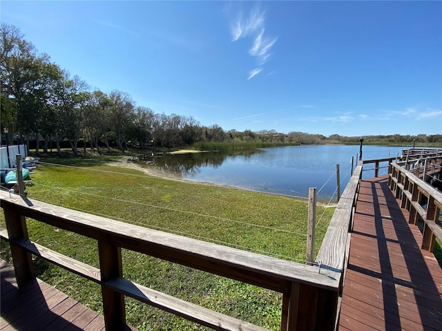 view of dock with a yard and a water view