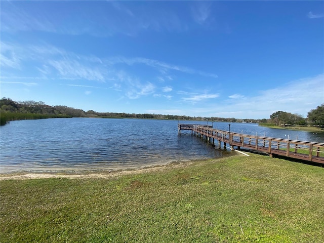 dock area with a lawn and a water view