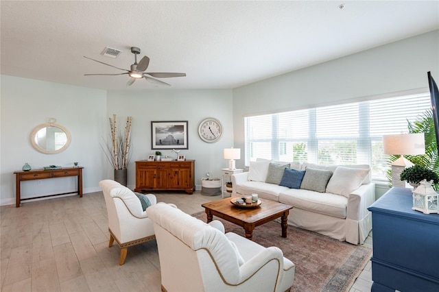 living room featuring ceiling fan, a textured ceiling, and light wood-type flooring