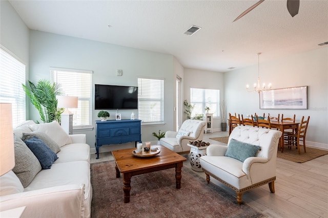 living room with hardwood / wood-style flooring and ceiling fan with notable chandelier