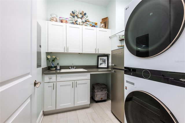 laundry area with sink, cabinets, and stacked washer and clothes dryer