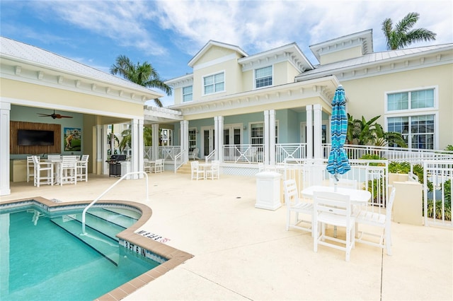 back of property with a patio, an outdoor bar, a community pool, and ceiling fan