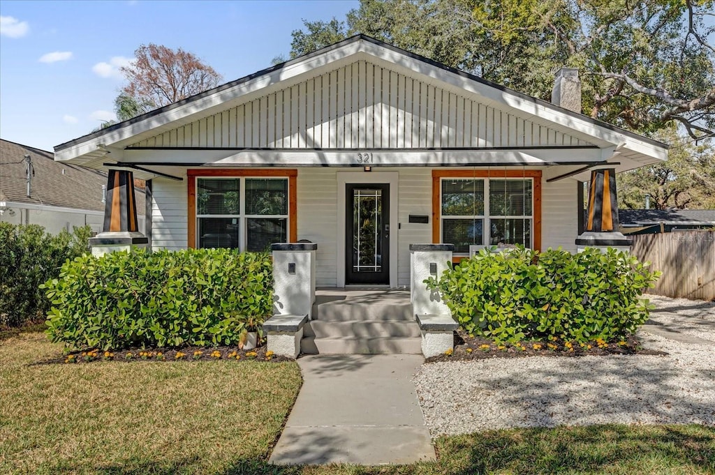 bungalow-style house featuring covered porch and a front yard