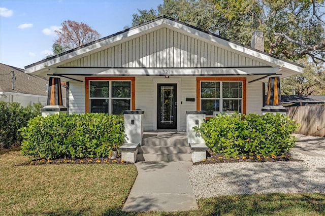 bungalow-style house featuring covered porch and a front yard