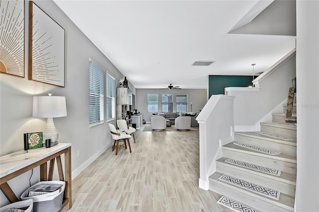 stairs with wood-type flooring and ceiling fan