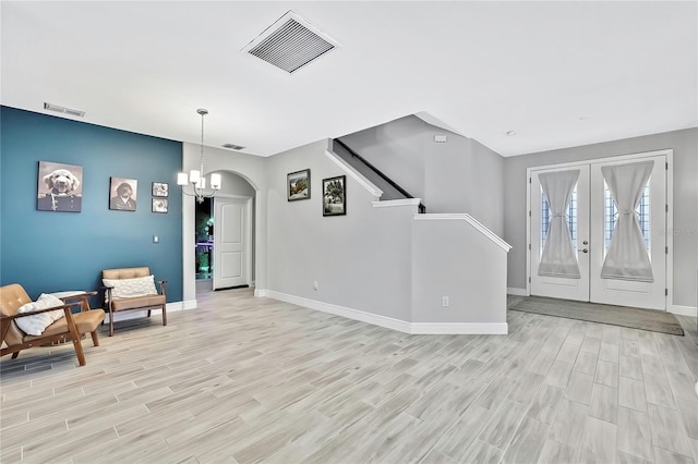 interior space featuring an inviting chandelier, light hardwood / wood-style flooring, and french doors