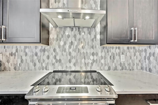 kitchen with electric stove, tasteful backsplash, light stone countertops, and wall chimney exhaust hood