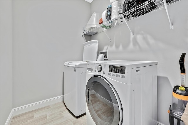 laundry room featuring separate washer and dryer and light hardwood / wood-style floors