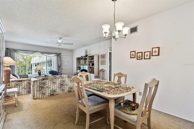 carpeted dining space featuring ceiling fan with notable chandelier and a textured ceiling