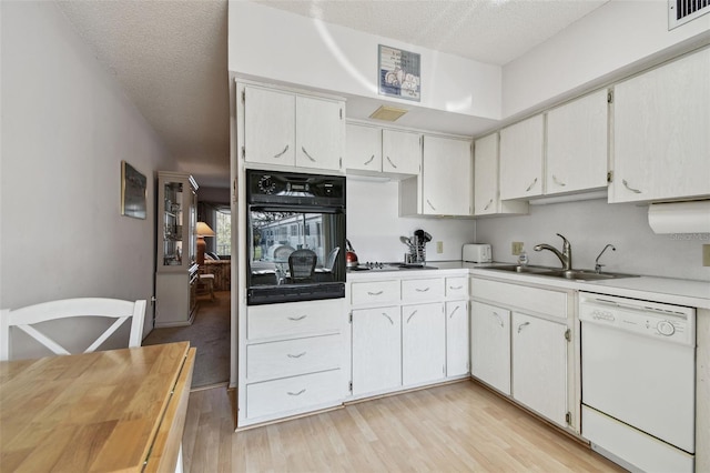 kitchen featuring sink, white dishwasher, oven, light hardwood / wood-style floors, and white cabinets