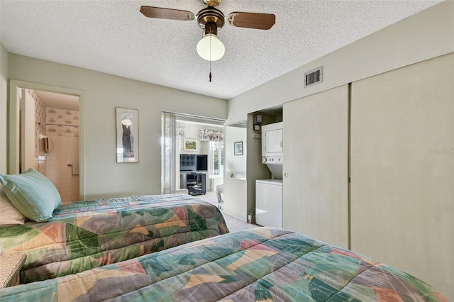 bedroom with stacked washer / dryer, carpet flooring, connected bathroom, and a textured ceiling