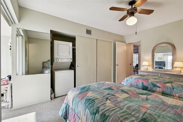 bedroom featuring stacked washer and dryer, light colored carpet, a textured ceiling, a closet, and ceiling fan