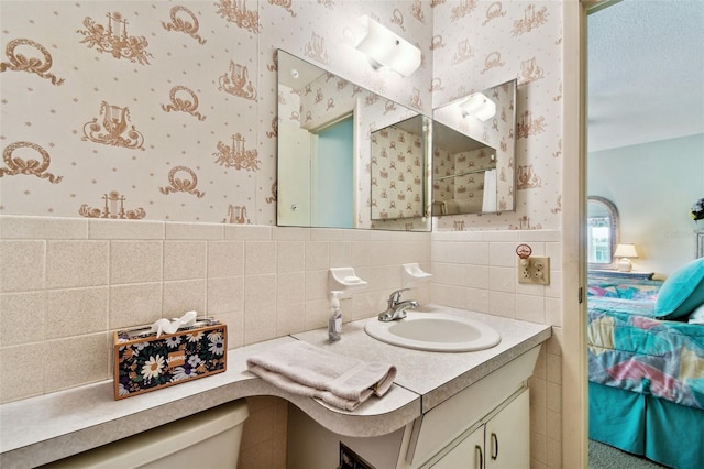 bathroom with vanity, tile walls, and toilet