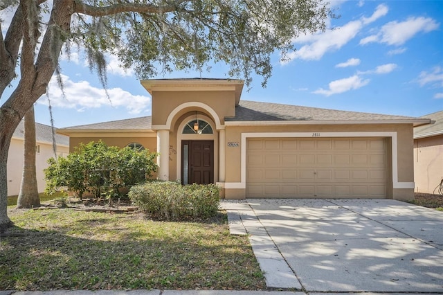 view of front facade with a garage, driveway, and stucco siding