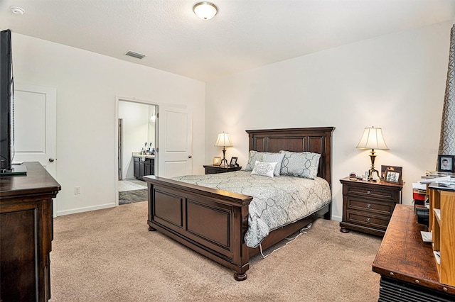 carpeted bedroom featuring a textured ceiling and ensuite bathroom