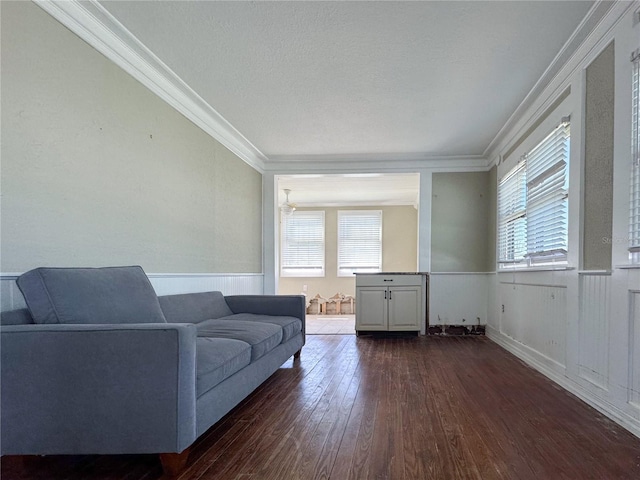 living room featuring dark wood-type flooring, ornamental molding, and a healthy amount of sunlight