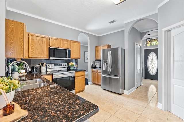 kitchen with appliances with stainless steel finishes, sink, decorative backsplash, ornamental molding, and light tile patterned floors