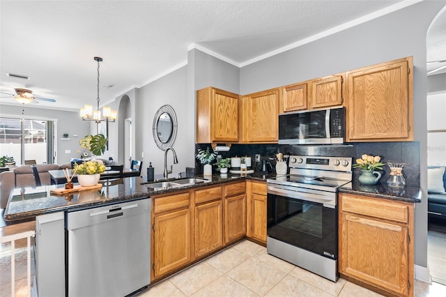 kitchen with appliances with stainless steel finishes, decorative light fixtures, sink, dark stone countertops, and kitchen peninsula