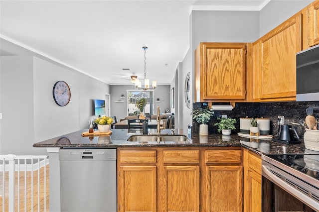 kitchen with sink, a notable chandelier, kitchen peninsula, stainless steel dishwasher, and dark stone counters