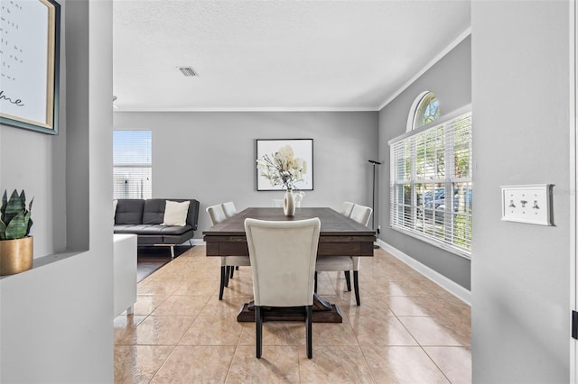 tiled dining area featuring plenty of natural light, ornamental molding, and a textured ceiling