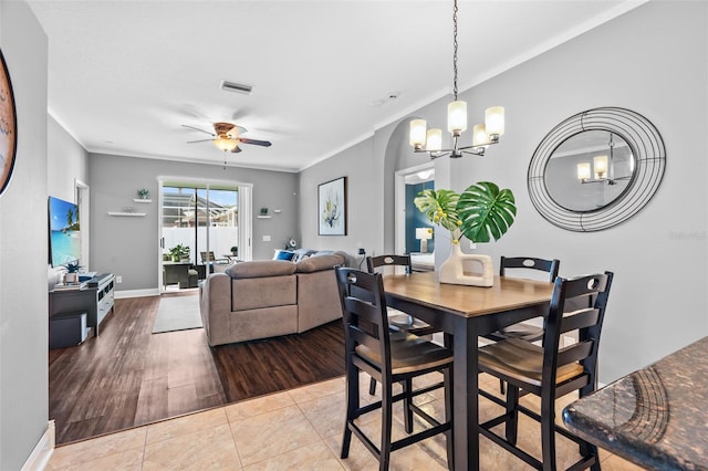 dining room with crown molding, tile patterned floors, and ceiling fan with notable chandelier