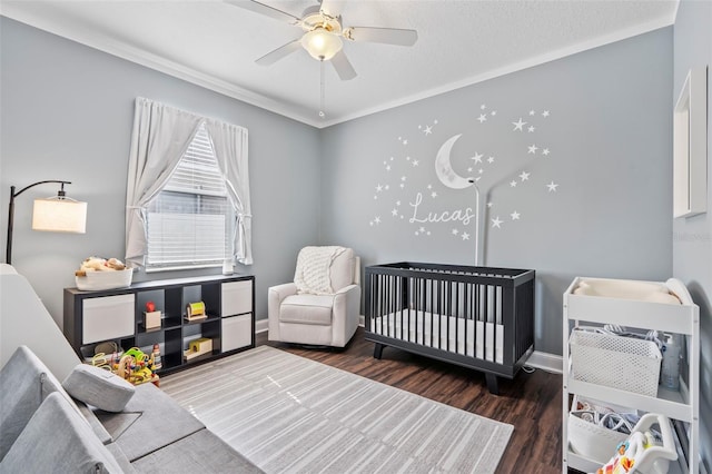 bedroom with ceiling fan, ornamental molding, dark hardwood / wood-style floors, and a crib