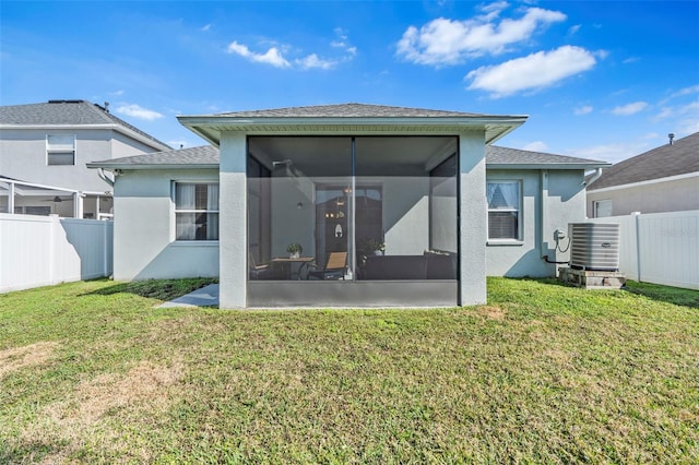 back of property with central air condition unit, a sunroom, and a lawn