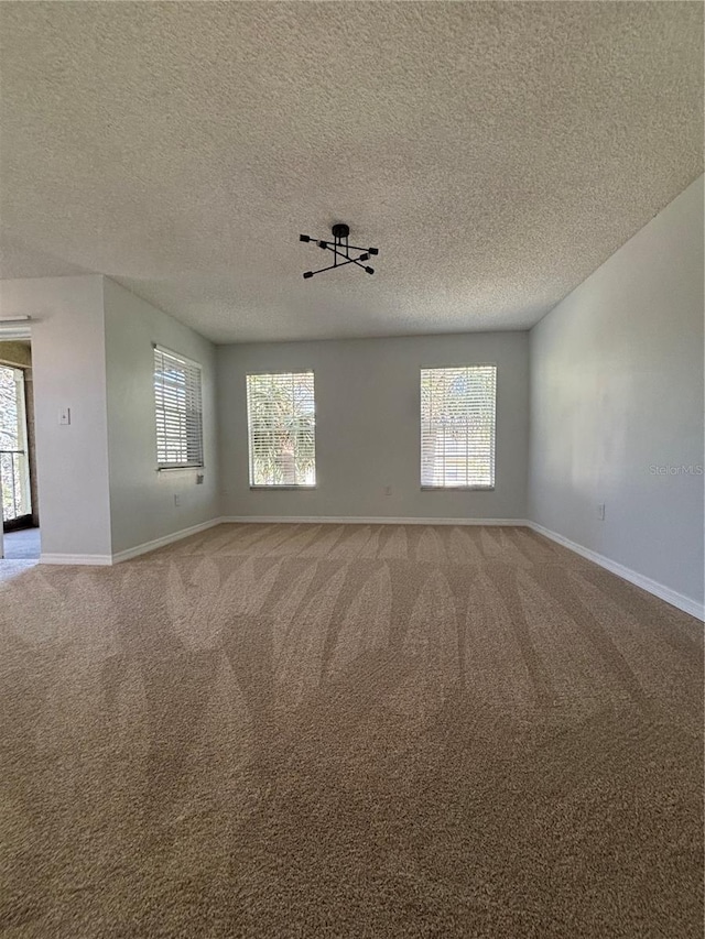 empty room featuring carpet, a healthy amount of sunlight, and a textured ceiling