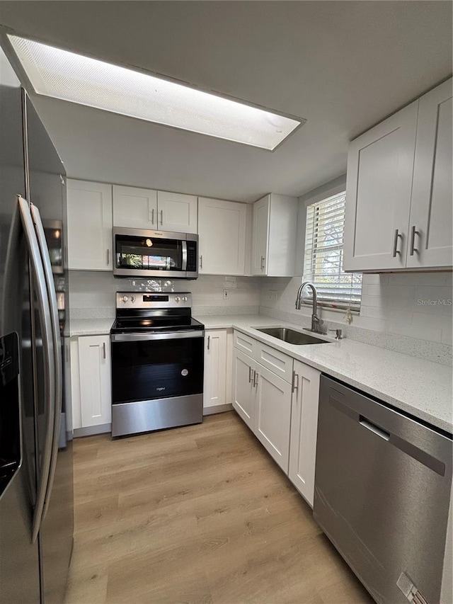 kitchen with appliances with stainless steel finishes, sink, and white cabinets